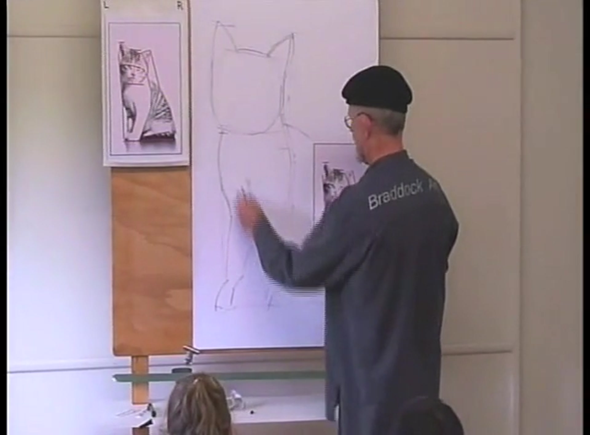Step 12 — Drawing the face and features (video frame from the lesson)